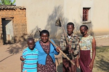 Spéciose Mukamurenzi und ihr Mann Jean Mbonyumugenzi arbeiten als  ehrenamtliche Familienhelfer in ihrem Heimatdorf. Hier: Mit ihren Kindern vor dem Haus.