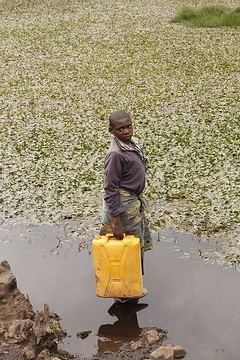 Ruanda, Vulkanpark Ruhengeri, Mädchen holt Wasser für die Landwirtschaft